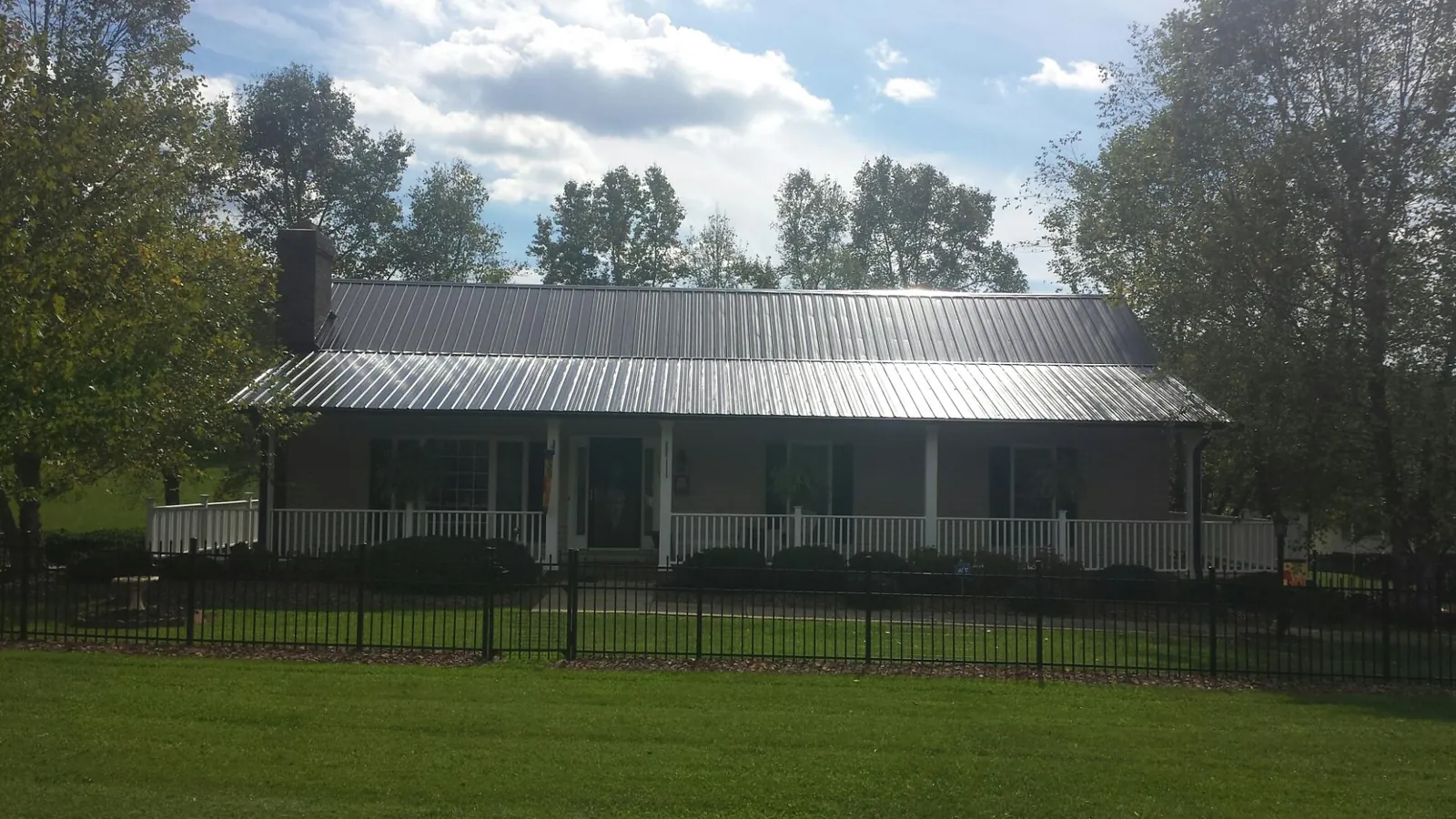 Gray metal roof on a brick ranch with a full width front porch — Gutter Guard Installation work by our crew in Benton